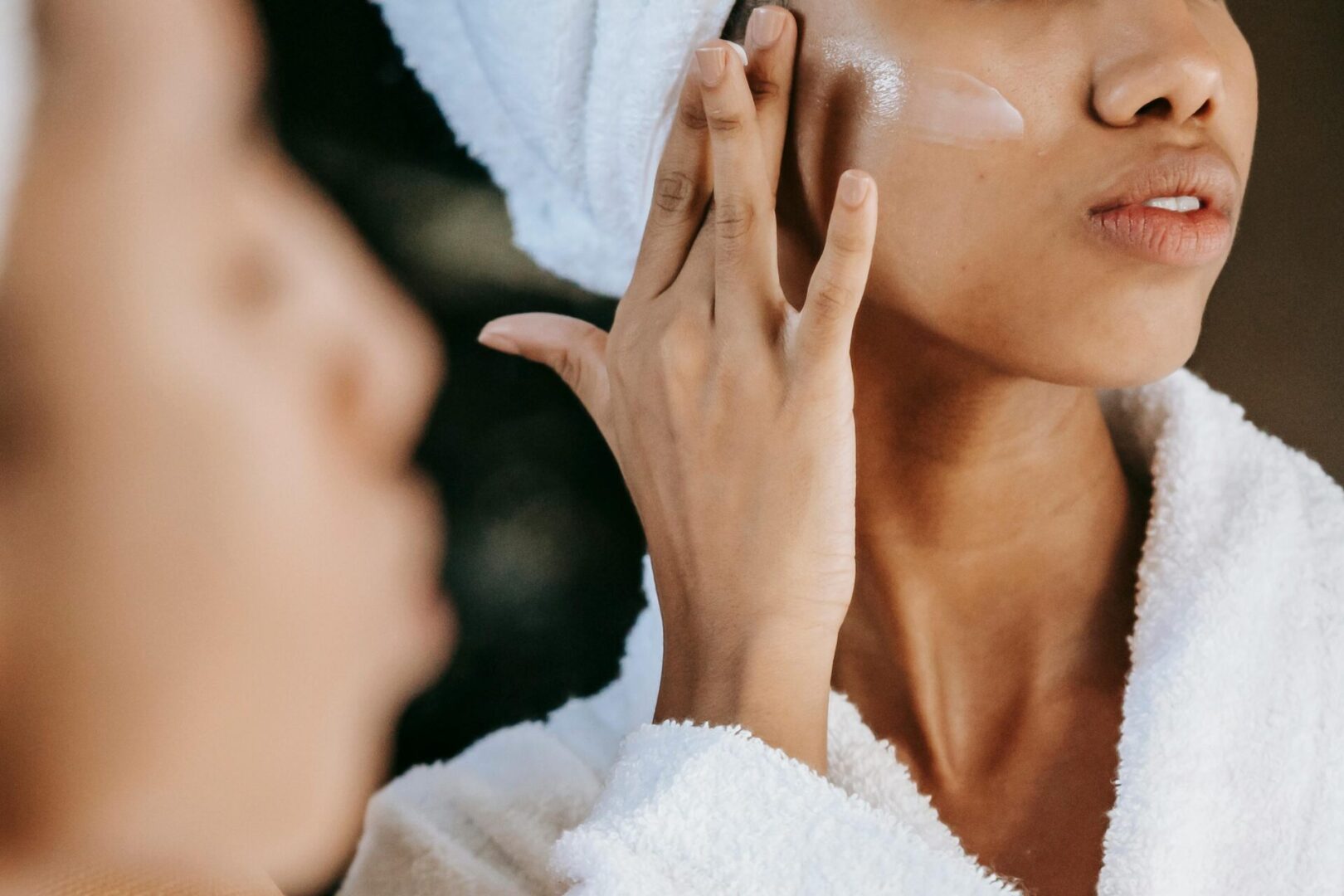 Woman applying moisturizer to her face.