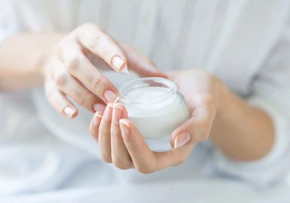 Woman's hands hold a jar of face cream.